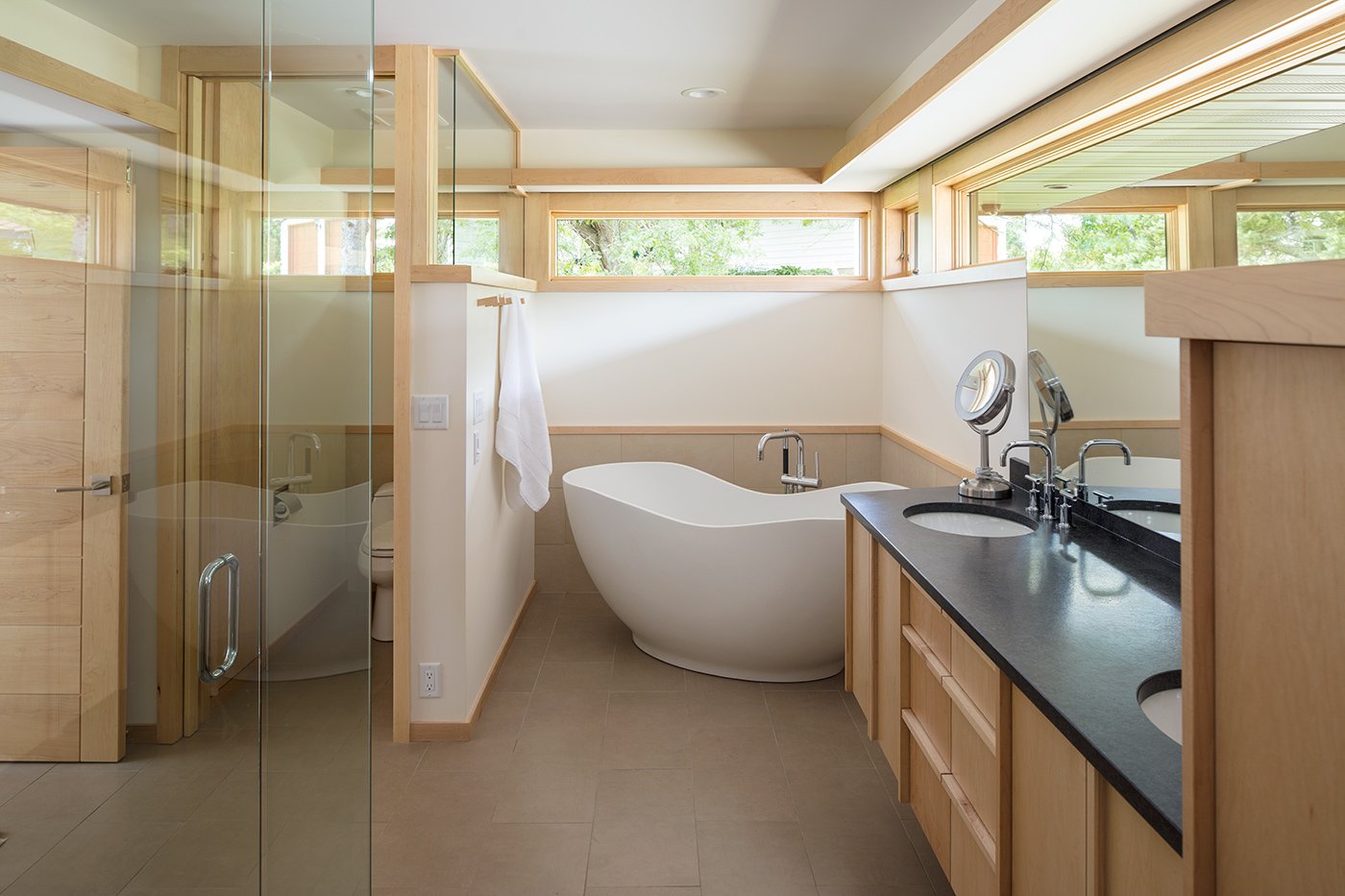 A bathroom with a soaking tub and high awning windows above.