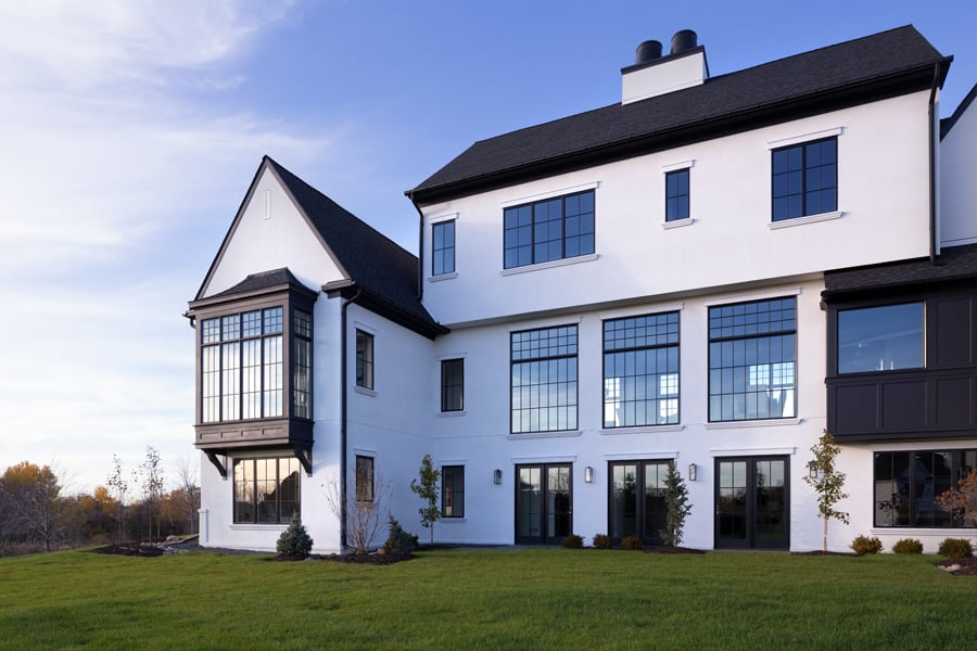 A modern Tudor with a white exterior and black Andersen® windows, including an oversized bay window.