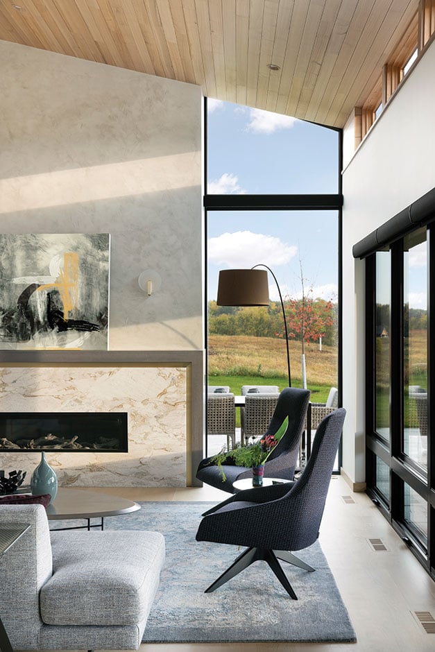 A floor-to-ceiling E-Series Picture Window next to a fireplace blurs the line between indoors and outdoors in this living room.