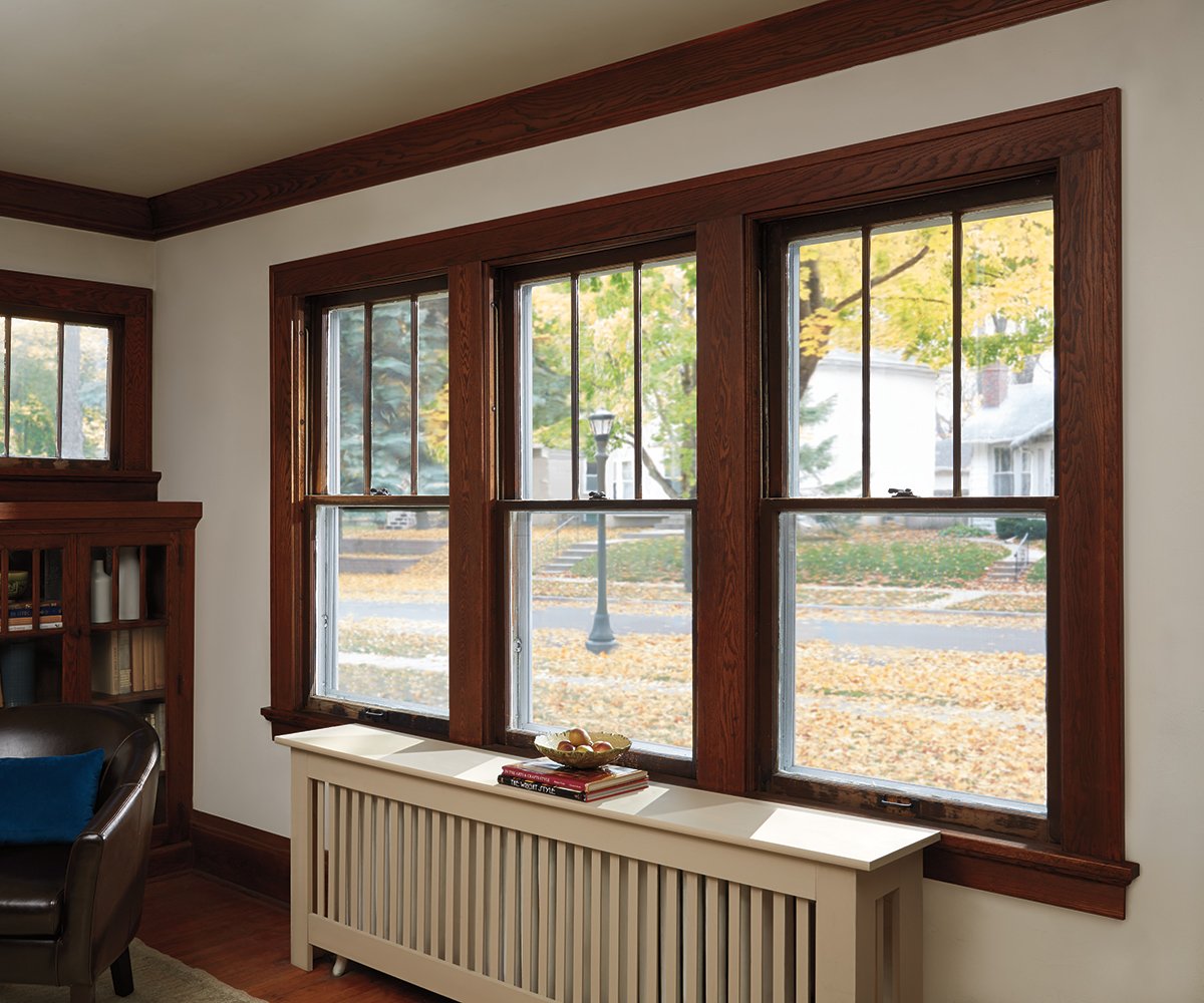 A living room with vinyl replacement windows on the left and with Andersen Woodwright Double-Hung Windows on the right.