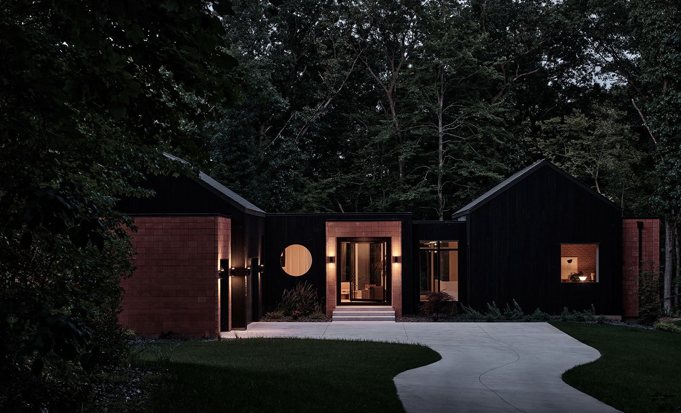 A black home with brick accents and a prominent Andersen® E-Series Specialty Window in the shape of a circle.