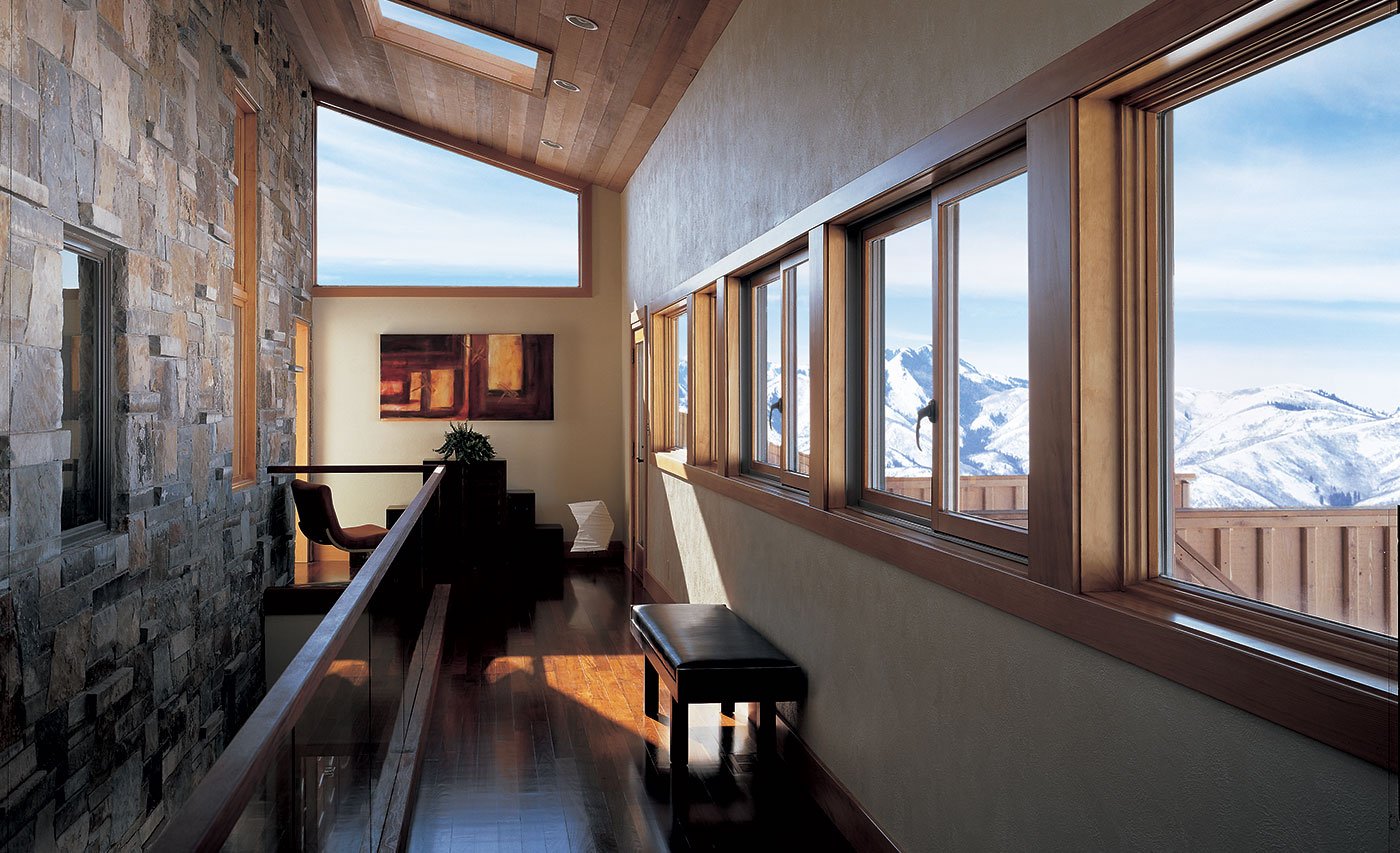 A hallway lined with Andersen® 400 Series Gliding Windows overlooking the mountains.