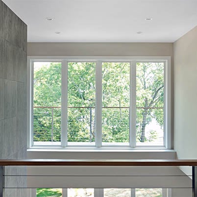 Interior of modern home with a balcony view through large, white Andersen Windows.