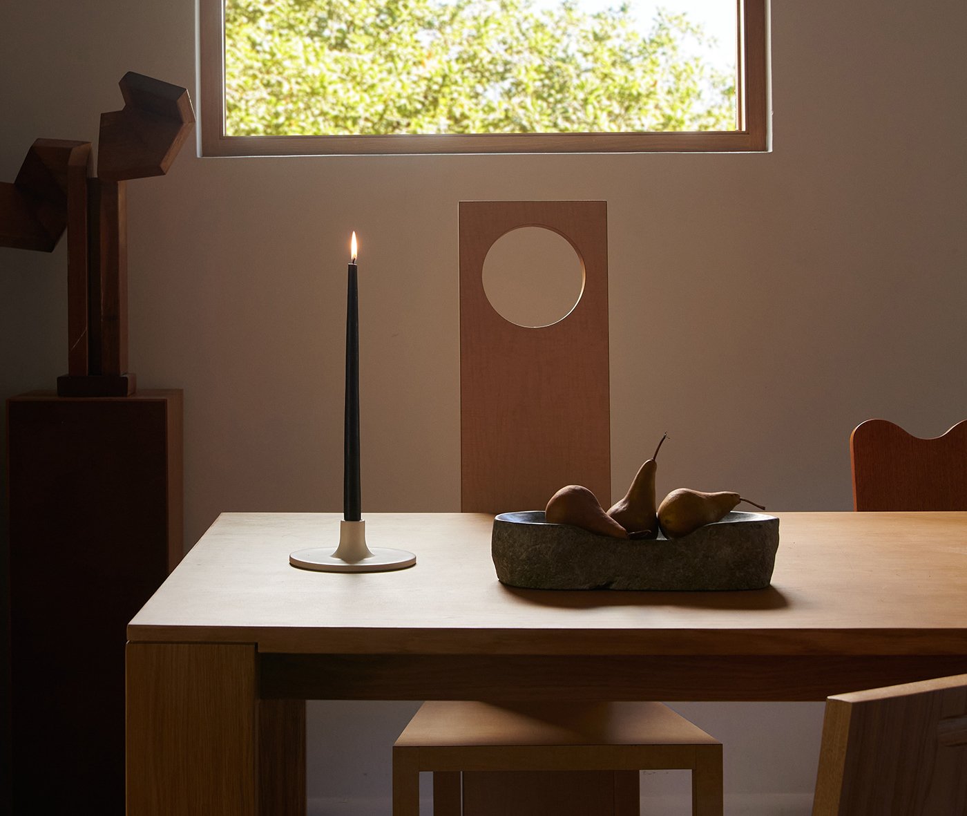 A moody dining room with a high window that lets in filtered light and preserves privacy.