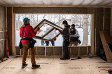 A construction crew install a window into a very large rough opening.